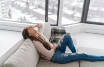woman with headache sad sitting on couch